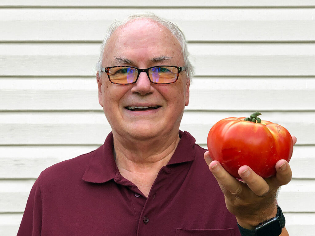 Terry Dunkle holding up a ripe, home-grown tomato