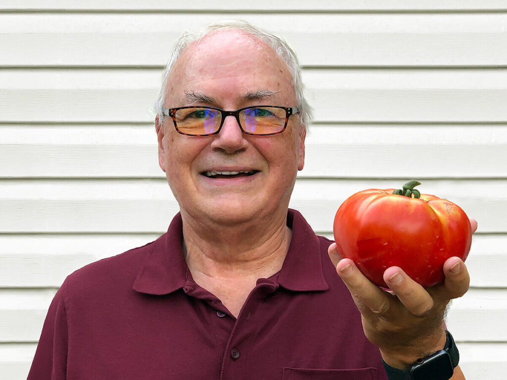 Terry Dunkle holding a large, home-grown tomato